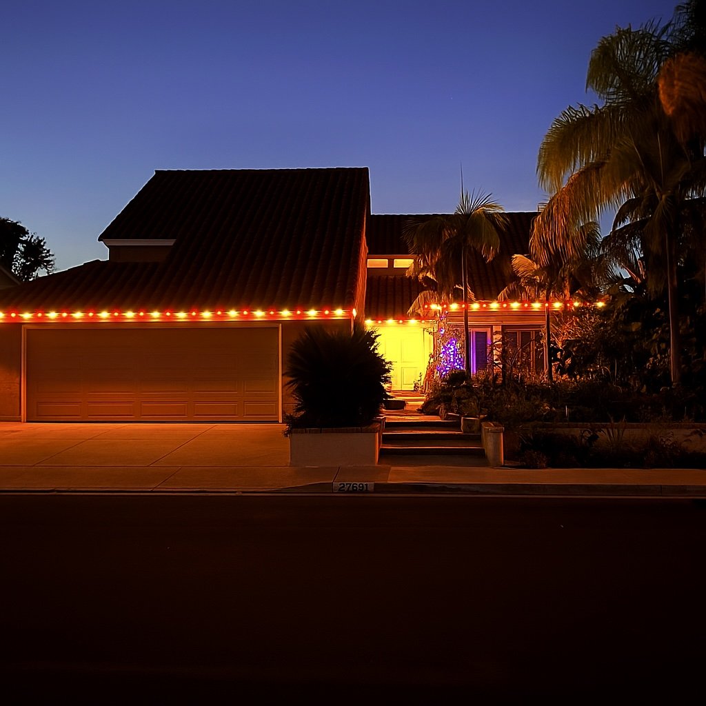Red C9 roofline lighting on a Spanish tile-roof home at dusk