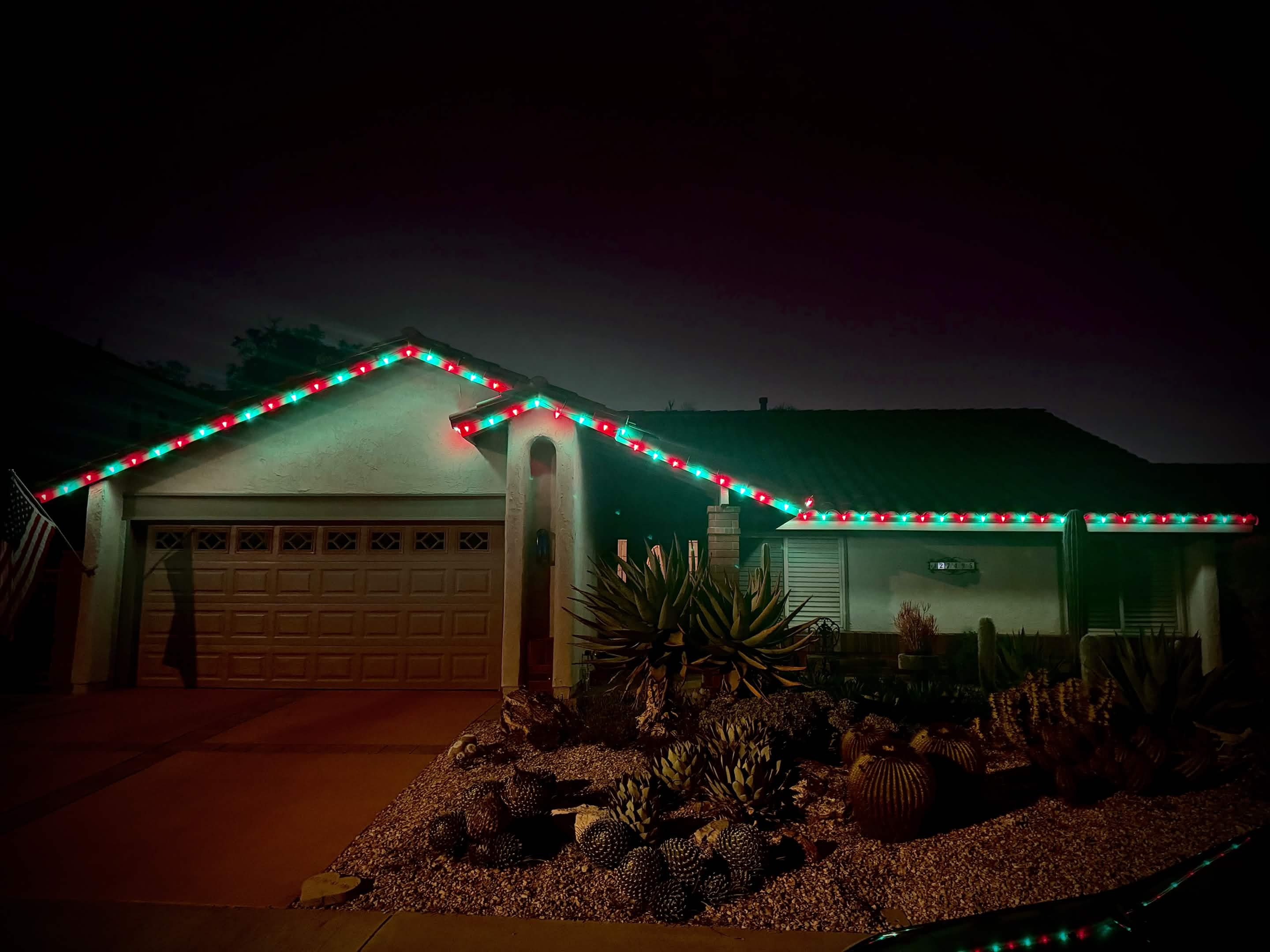 Red and green C9 roofline lighting on a desert-landscaped ranch home